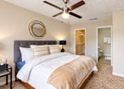 Thumbnail 4 of 18 - Furnished bedroom with a ceiling fan, walk-in closet opening, and nearby bathroom at Icon Cartersville Apartments.