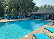 Thumbnail 5 of 22 - A pool with blue chairs and a building in the background.