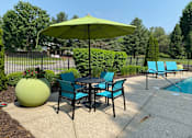 Thumbnail 7 of 22 - A green umbrella is above a table with chairs around it.