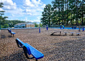 Thumbnail 8 of 17 - A playground with blue benches and a swing set.