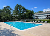 Thumbnail 6 of 17 - A large swimming pool surrounded by trees and lounge chairs.