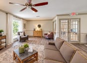 Thumbnail 15 of 15 - A living room with a brown couch, a coffee table, and a ceiling fan.