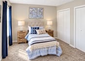 Thumbnail 5 of 15 - Bedroom with carpet, closet storage, and blue-accented furnishings at Madison Park Apartments & Townhomes in Birmingham, AL.