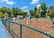 Thumbnail 12 of 15 - A playground with a blue slide and a green fence.