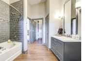 Thumbnail 4 of 19 - A bathroom with a white sink and a grey tiled wall.
