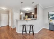Thumbnail 16 of 34 - a kitchen with a bar and two stools in front of a kitchen counter