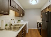 Thumbnail 2 of 23 - A kitchen with a black refrigerator and brown cabinets.