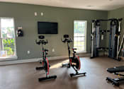 Thumbnail 16 of 24 - A home gym with exercise equipment and a television.