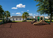 Thumbnail 14 of 24 - A playground with a green slide and a brown ground.