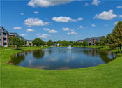 Thumbnail 13 of 24 - A serene landscape featuring a pond, a fountain, and a row of buildings.