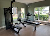 Thumbnail 18 of 24 - A gym with a treadmill, a stationary bike, and a weight machine.