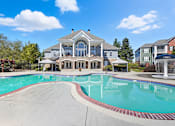 Thumbnail 7 of 30 - A large house with a pool in front.