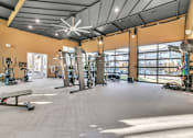Thumbnail 9 of 25 - A gym with a variety of exercise equipment and a large mirror on the wall.