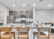 Thumbnail 12 of 25 - A modern kitchen with wooden chairs and a marble countertop.