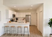 Thumbnail 1 of 16 - A kitchen with white cabinets and a white island with three bar stools.