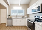 Thumbnail 5 of 16 - A kitchen with white cabinets and black appliances.