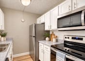 Thumbnail 12 of 24 - Galley kitchen with white cabinets and a refrigerator at Waterchase Apartments in Largo, FL.