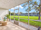 Thumbnail 20 of 24 - Exterior of Waterchase Apartments in Largo, FL, with trees beneath a blue sky.