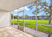 Thumbnail 21 of 24 - A room with a view of a grassy area and a building through the window.