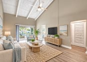 Thumbnail 4 of 24 - Virtually staged living room with a vaulted ceiling, exposed beams and sliding balcony doors at Waterchase Apartments in Largo, FL.