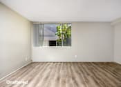 Thumbnail 4 of 45 - A room with wooden flooring and a window showing trees outside.