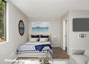 Thumbnail 18 of 57 - A bedroom with a bed, a couch, and a painting of a beach scene on the wall.