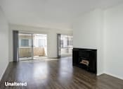 Thumbnail 7 of 19 - A room with a black fireplace and wooden floors.
