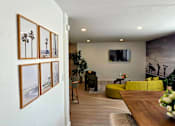 Thumbnail 8 of 57 - A living room with a yellow couch and a painting of a palm tree on the wall.