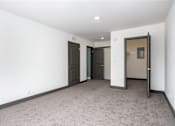 Thumbnail 45 of 52 - an empty living room with white walls and grey carpet and two doors to different rooms
