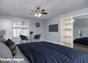 Thumbnail 11 of 36 - A bedroom with a bed, a table with chairs, a clock, and a shelf.