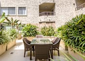 Thumbnail 10 of 33 - A patio with a table and chairs surrounded by green plants.
