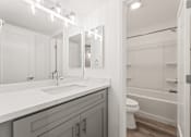 Thumbnail 9 of 33 - A white bathroom with a sink, mirror, and toilet.