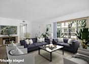 Thumbnail 11 of 41 - A living room with a grey couch and a glass coffee table.