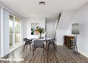 Thumbnail 13 of 23 - A modern dining room with a wooden floor and white walls.