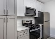Thumbnail 18 of 63 - a kitchen with white cabinets and a stove and a microwave