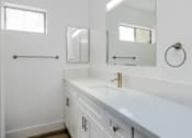 Thumbnail 27 of 63 - a bathroom with white cabinets and a sink and a mirror
