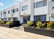 Thumbnail 1 of 18 - an apartment building with a sidewalk and plants in front of it