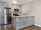 Thumbnail 25 of 45 - A kitchen with a stainless steel refrigerator and a white countertop.
