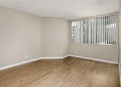 Thumbnail 30 of 45 - Empty room with wooden floor and a window with blinds.