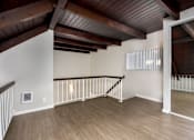 Thumbnail 43 of 45 - A room with a wooden floor and a staircase with a railing.