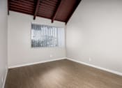 Thumbnail 37 of 45 - Empty room with wooden floor and a window with blinds.