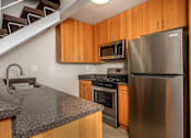 Thumbnail 38 of 45 - A kitchen with a stainless steel refrigerator and wooden cabinets.