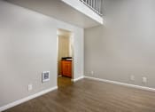 Thumbnail 39 of 45 - A room with a wooden floor and a white wall with a doorway leading to another room.