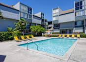 Thumbnail 2 of 45 - a swimming pool with yellow chairs in front of an apartment building