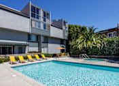 Thumbnail 10 of 45 - a swimming pool with yellow chairs in front of a building