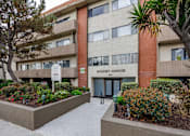 Thumbnail 1 of 19 - an apartment building with a sidewalk and garden in front of it