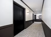 Thumbnail 28 of 52 - a hallway with black doors and white walls and a carpeted floor