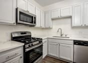 Thumbnail 17 of 34 - A kitchen with white cabinets and a black stove top oven.