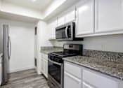 Thumbnail 27 of 53 - A kitchen with a granite countertop and white cabinets.