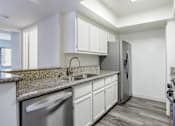 Thumbnail 28 of 53 - A kitchen with a granite countertop and stainless steel appliances.